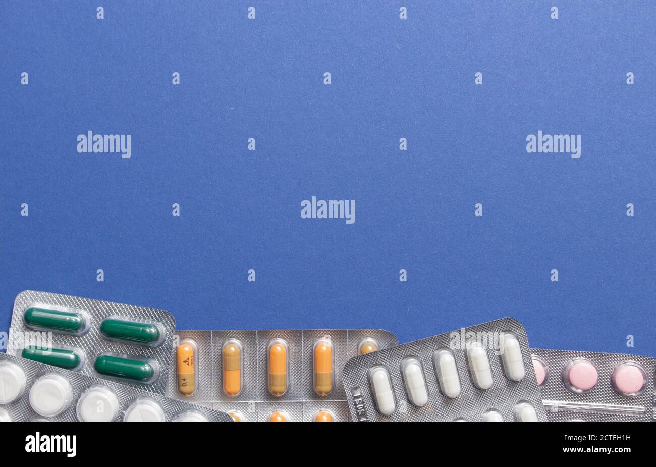 Different medicines tablets, pills in blister pack, medications drugs on blue background. Close