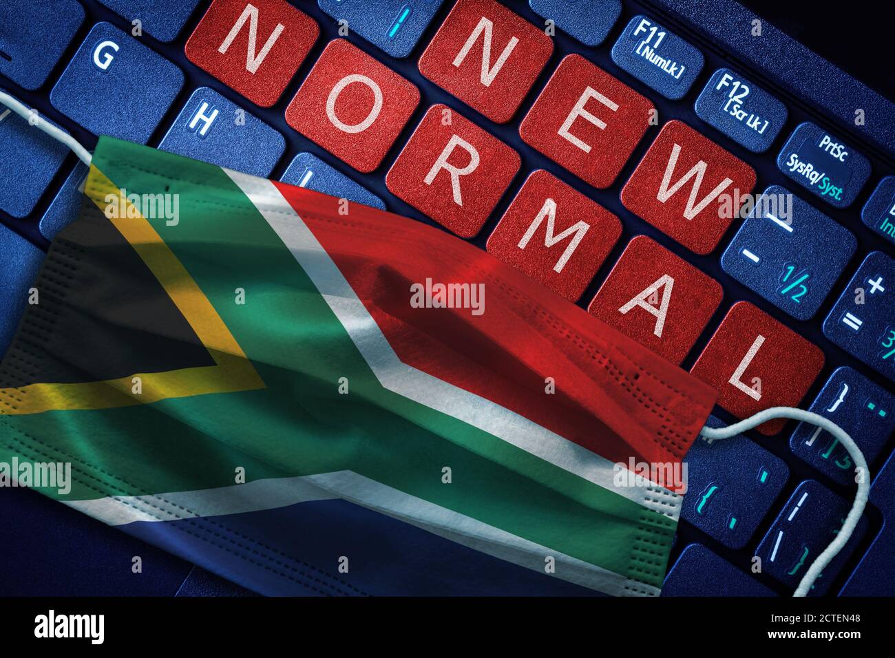 COVID-19 coronavirus new normal concept in South Africa as shown by South African flag on face mask with New Normal on laptop red alert keyboard butto Stock Photo