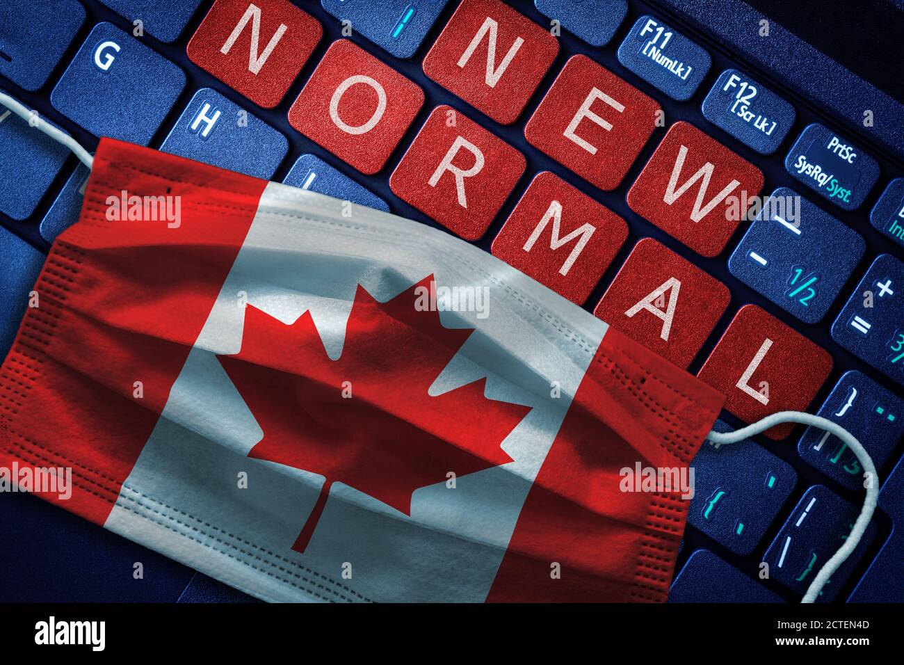 COVID-19 coronavirus new normal concept in Canada as shown by Canadian flag on face mask with New Normal on laptop red alert keyboard buttons. Stock Photo
