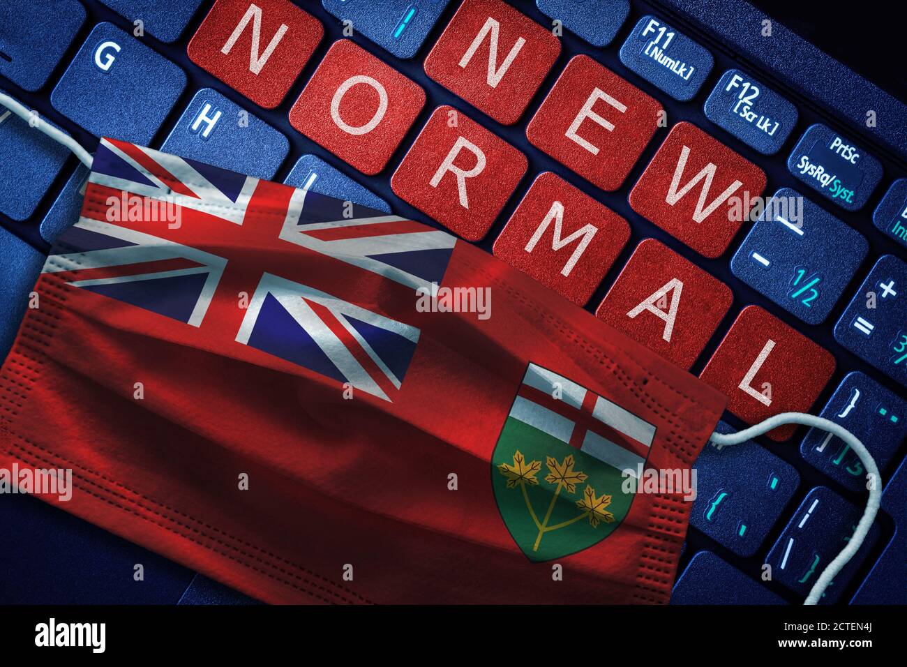 COVID-19 coronavirus new normal concept in the Canadian province of Ontario as shown by Ontario flag on face mask with New Normal on laptop red alert Stock Photo