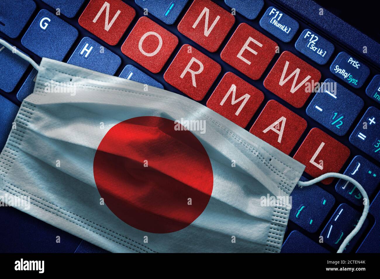 COVID-19 coronavirus new normal concept in Japan as shown by Japanese flag on face mask with New Normal on laptop red alert keyboard buttons. Stock Photo