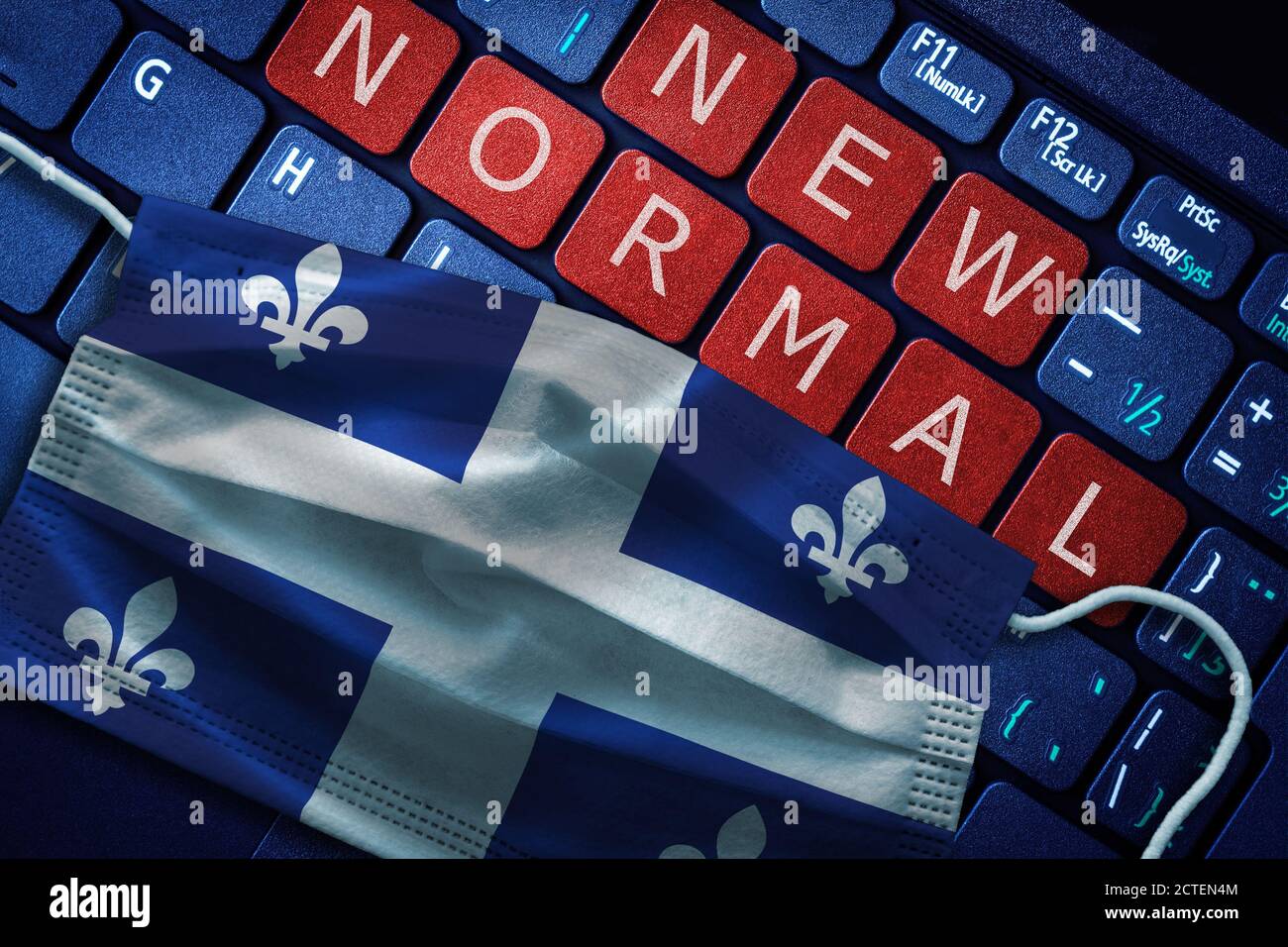 COVID-19 coronavirus new normal concept in the Canadian province of Quebec as shown by Quebec flag on face mask with New Normal on laptop red alert ke Stock Photo
