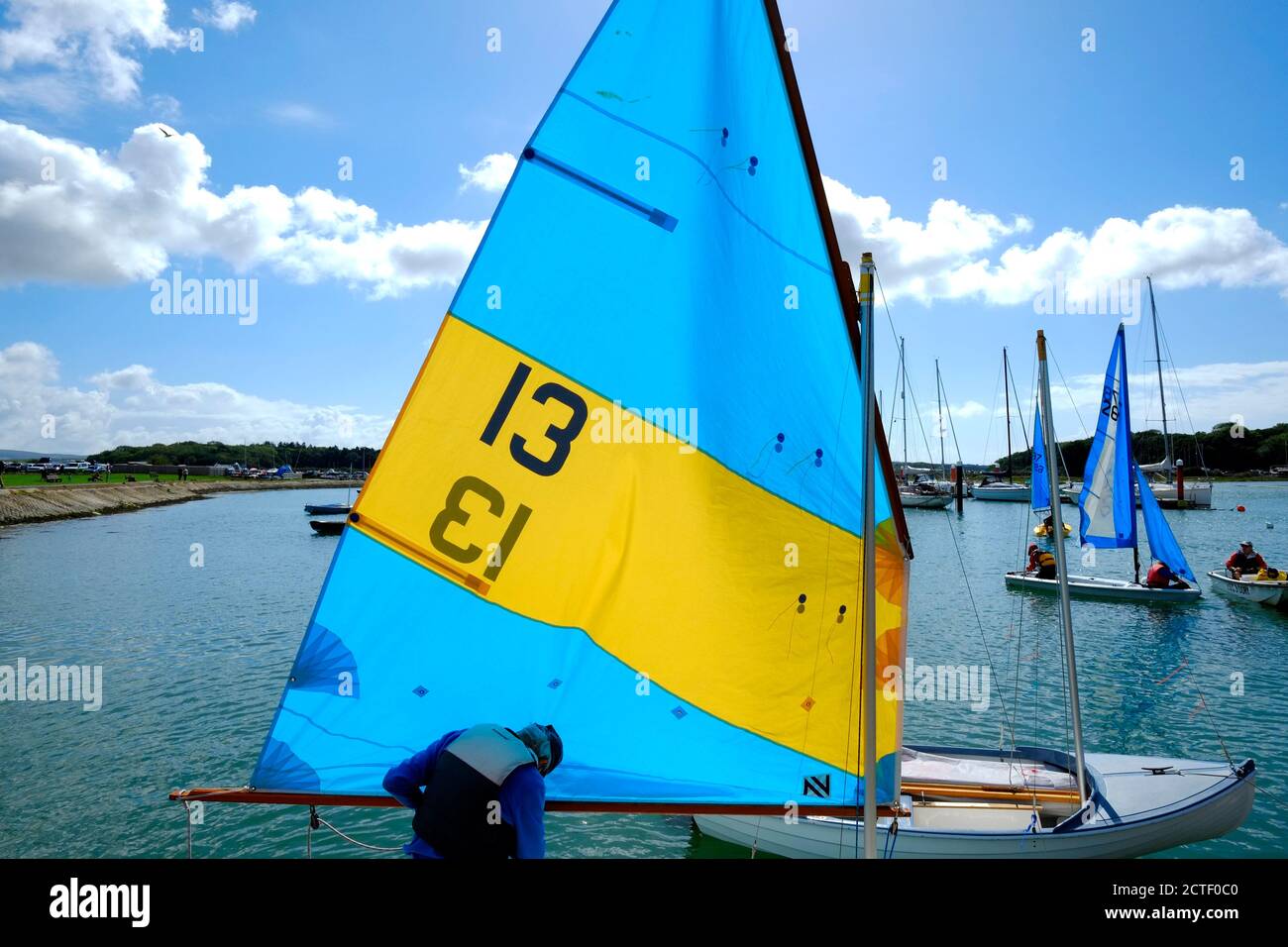 Sailing dinghies with colourful sails up congregating around the slipway on the Yar estuary at