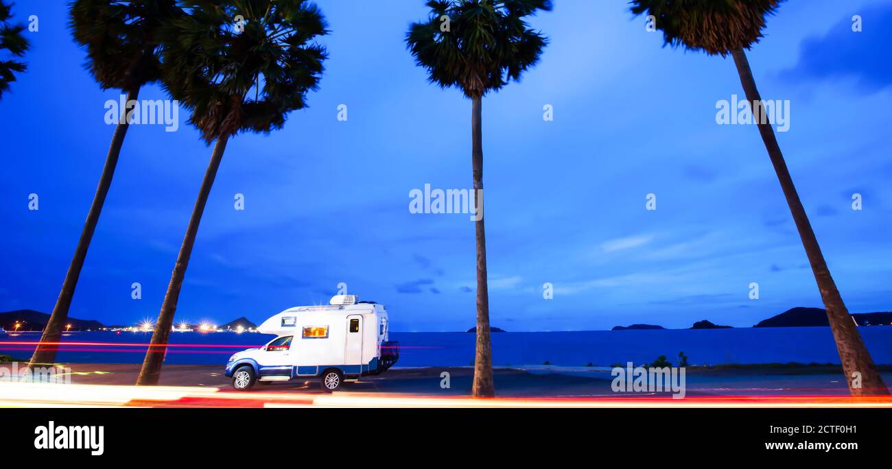 Journey in motorhome on the road trip to palm beach in summer, abstract lights trails on the road at twilight. Long exposure. Vacations concepts. Stock Photo