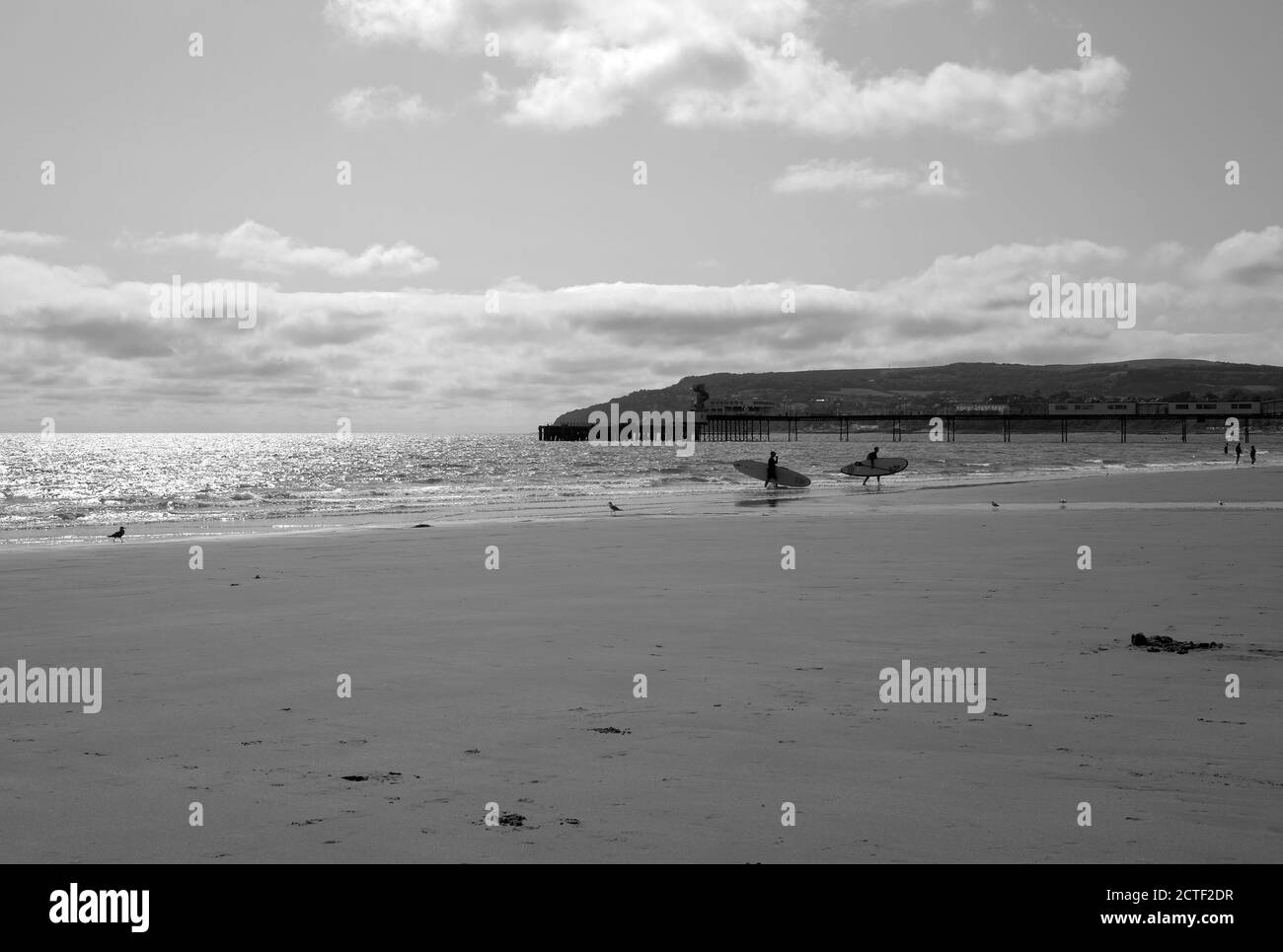Sandown seafront Isle of Wight two people carrying paddle boards out of