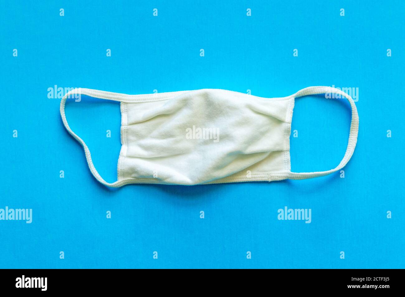 A white cloth face mask is isolated on a blue background Stock Photo