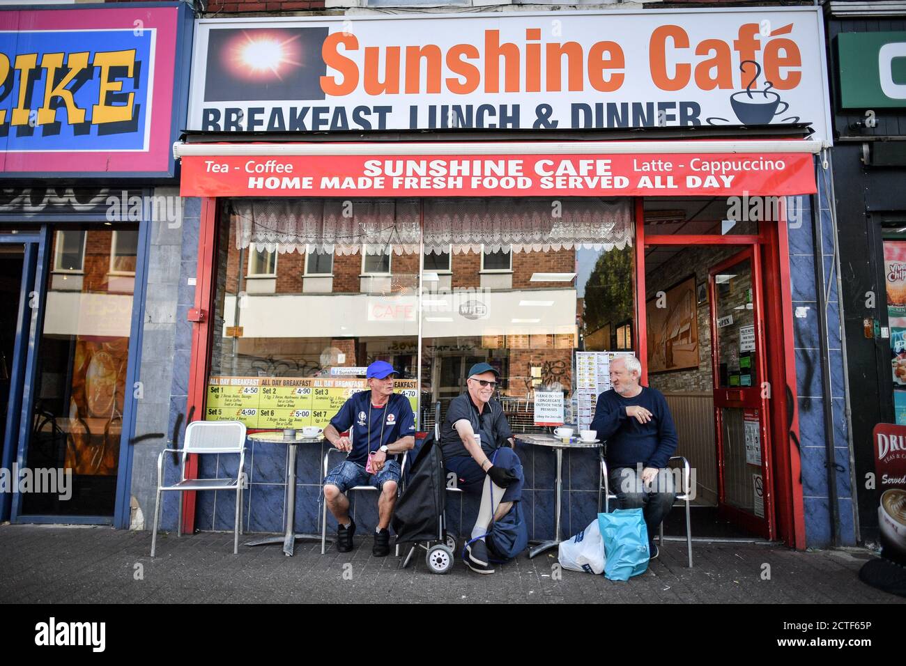 The changing face of the high street. Three customers relax outside the Sunshine Cafe on East Street in Bedminster, Bristol, where tables and chairs for outside dining are now more commonplace for even the smallest of establishments due to coronavirus rules, some six months on from the evening of March 23 when Prime Minister Boris Johnson announced nationwide restrictions. Stock Photo
