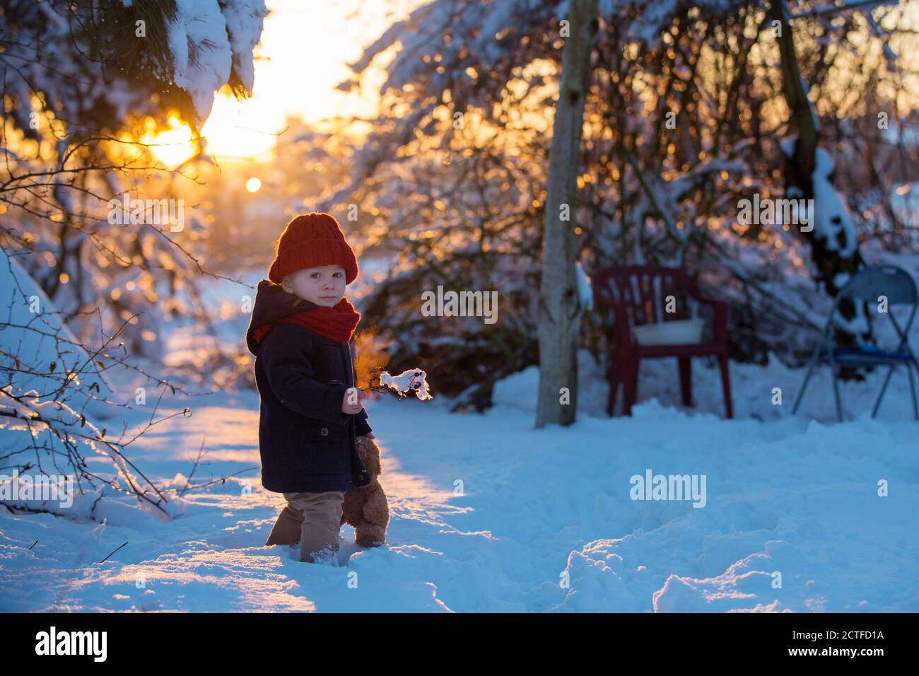Baby playing with teddy in the snow, winter time. Little toddler boy in ...