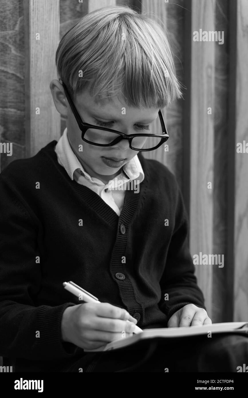 a child with glasses makes notes in a notebook. monochrome image Stock Photo