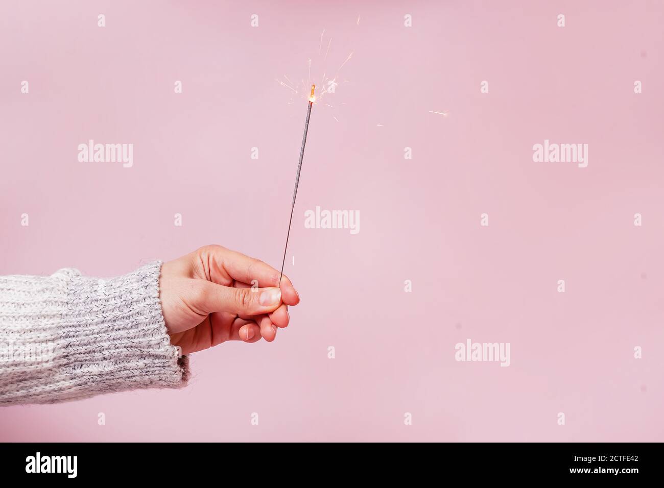 Female hand in sweater holding festive Christmas sparkler Stock Photo