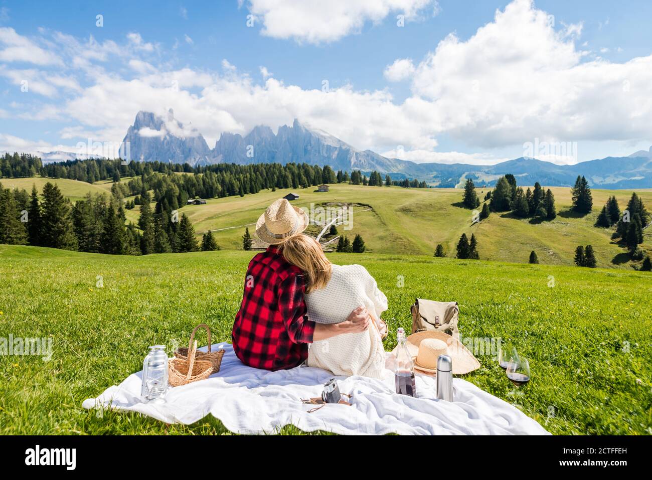 Romantic couple visiting Alpe di Siusi mountains, Italy. Boyfriend and girlfriend in love enjoying picnic time together - Bright filter Stock Photo