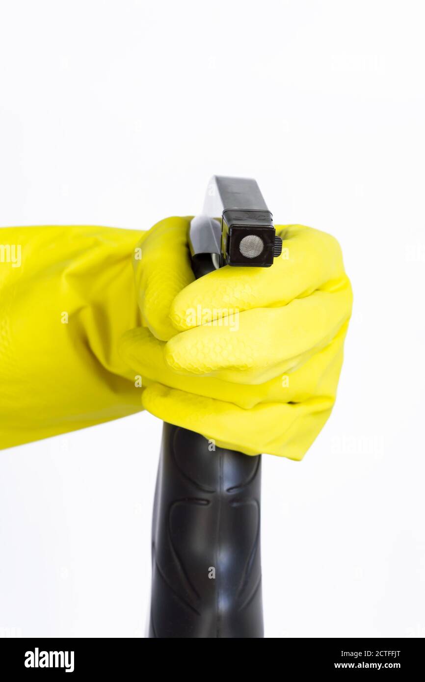 hand in yellow rubber glove holding black plastic spray detergent ...