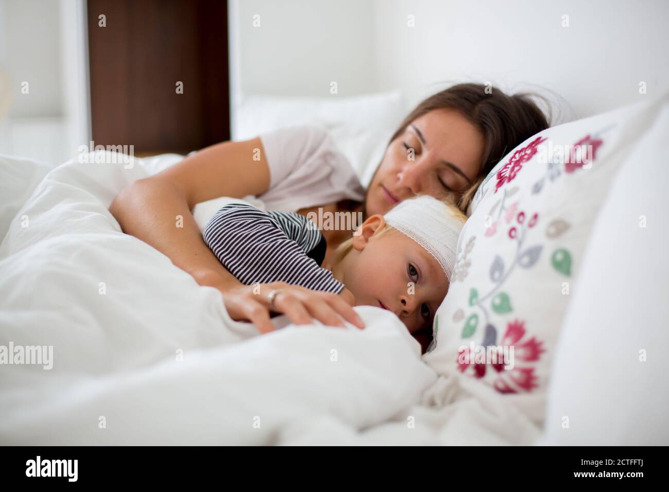 Little toddler boy with head injury, lying in bed, tired, sleeping