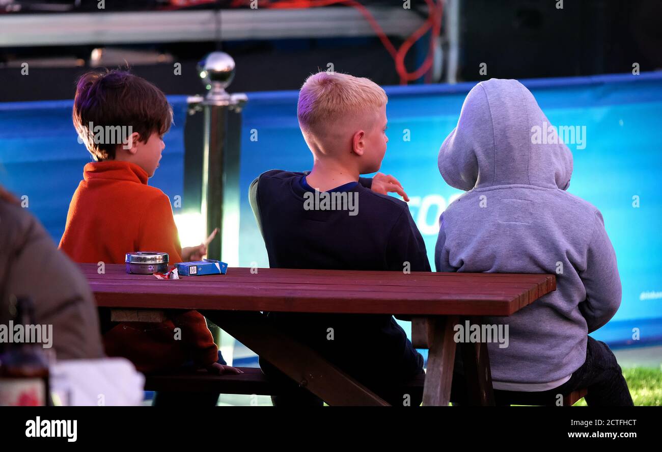 three young boys watching outdoor show in public house garden. Stock Photo