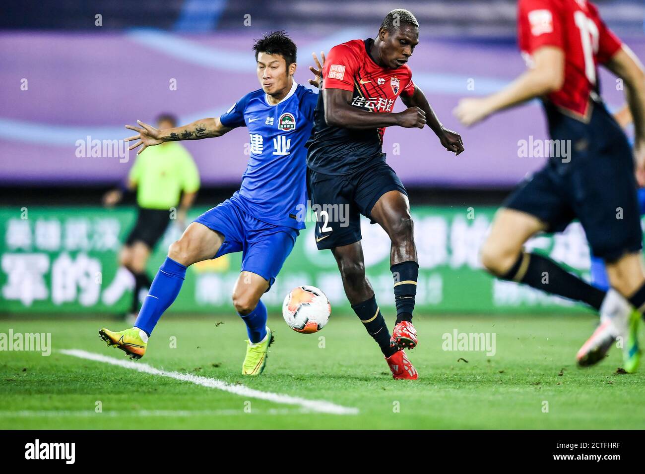 Cameroonian football player John Mary of Shenzhen F.C., right, struggles for the ball during the fourth-round match of 2020 Chinese Super League (CSL) Stock Photo