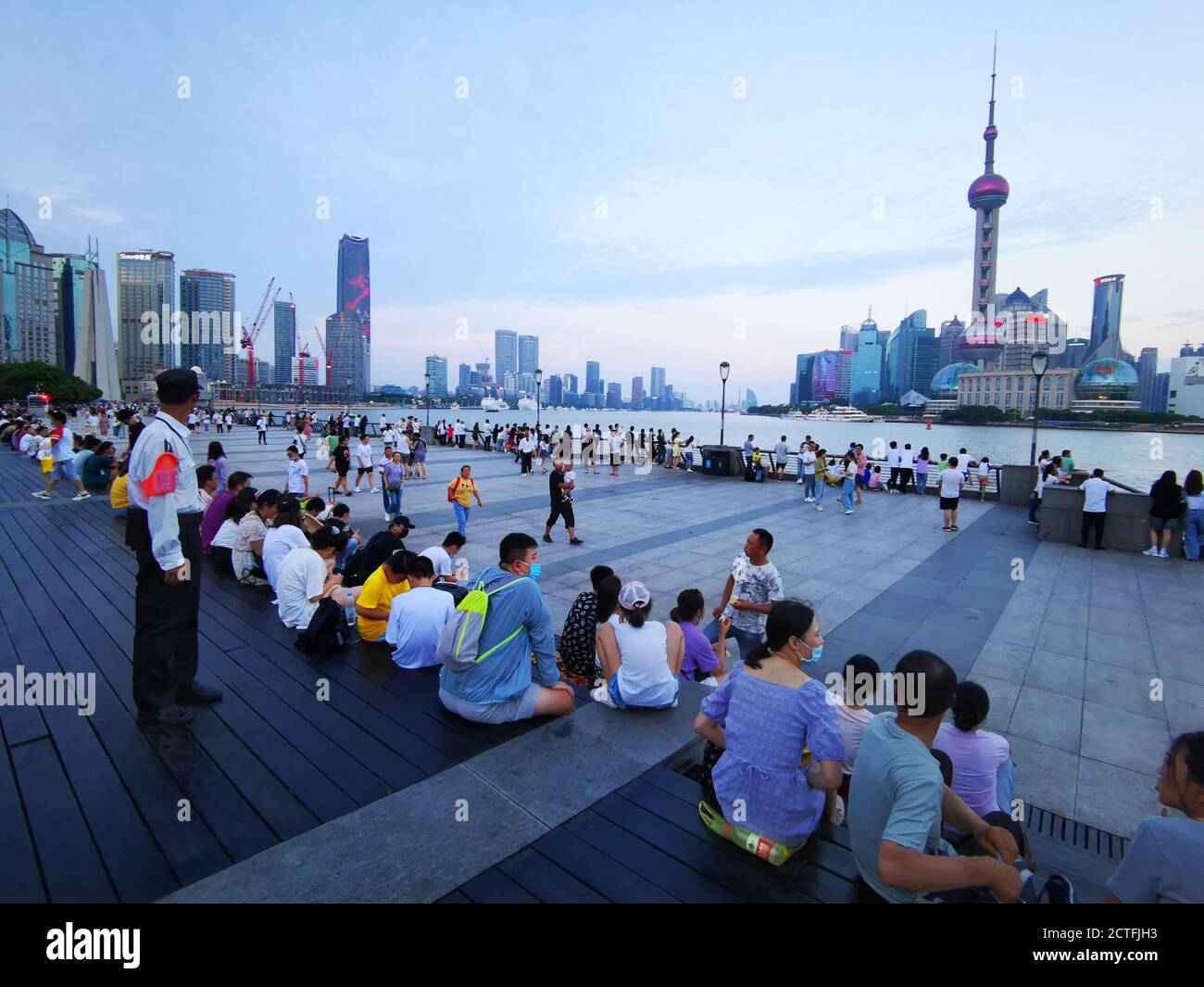 A group of tourists sit on the steps at sunset, as the temperature was too day during the daytime, to enjoy the astonishing skyline of Shanghai, China Stock Photo