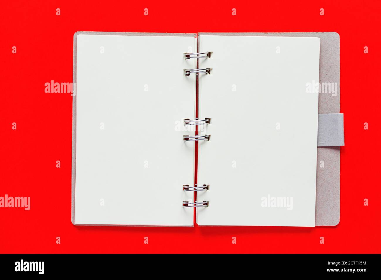 Clean spiral note book for notes and messages on red background. Minimal business flat lay Stock Photo