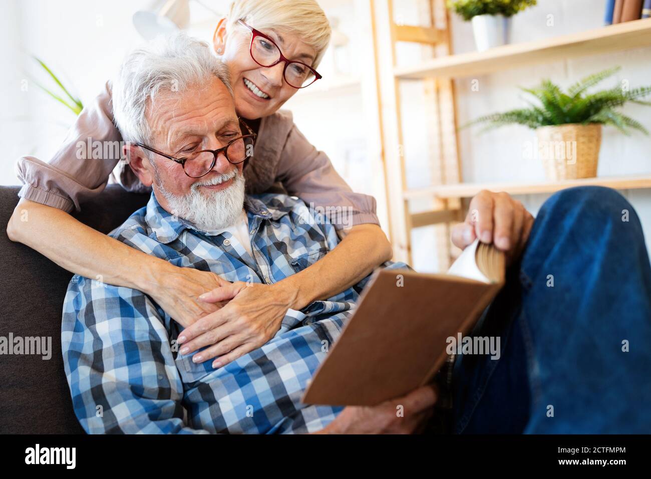 Mature couple relaxing at home and reading book together Stock Photo