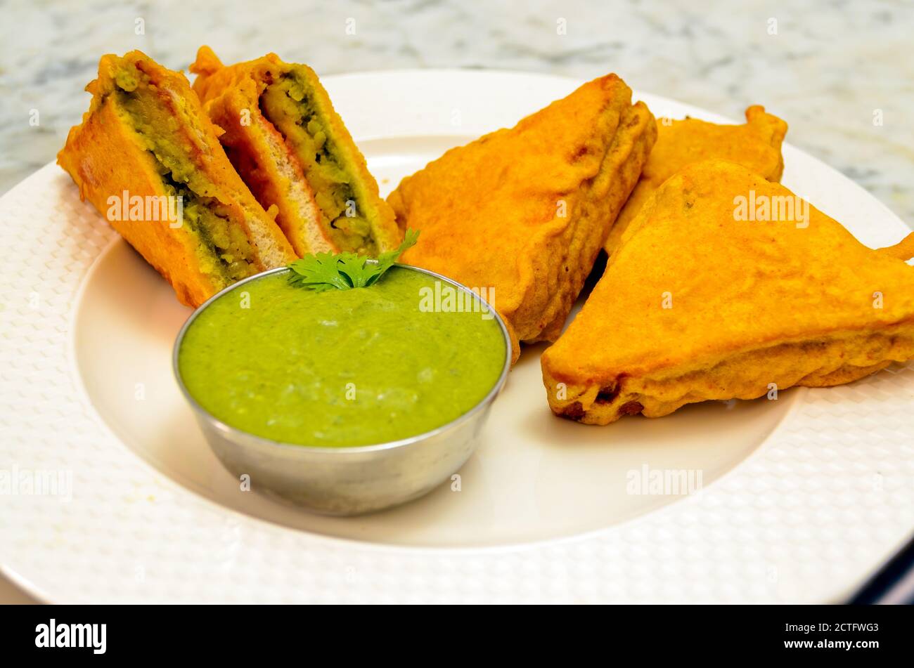 Delicious Bread Pakoda in a round white Plate along with Green Coriander Chutney Stock Photo