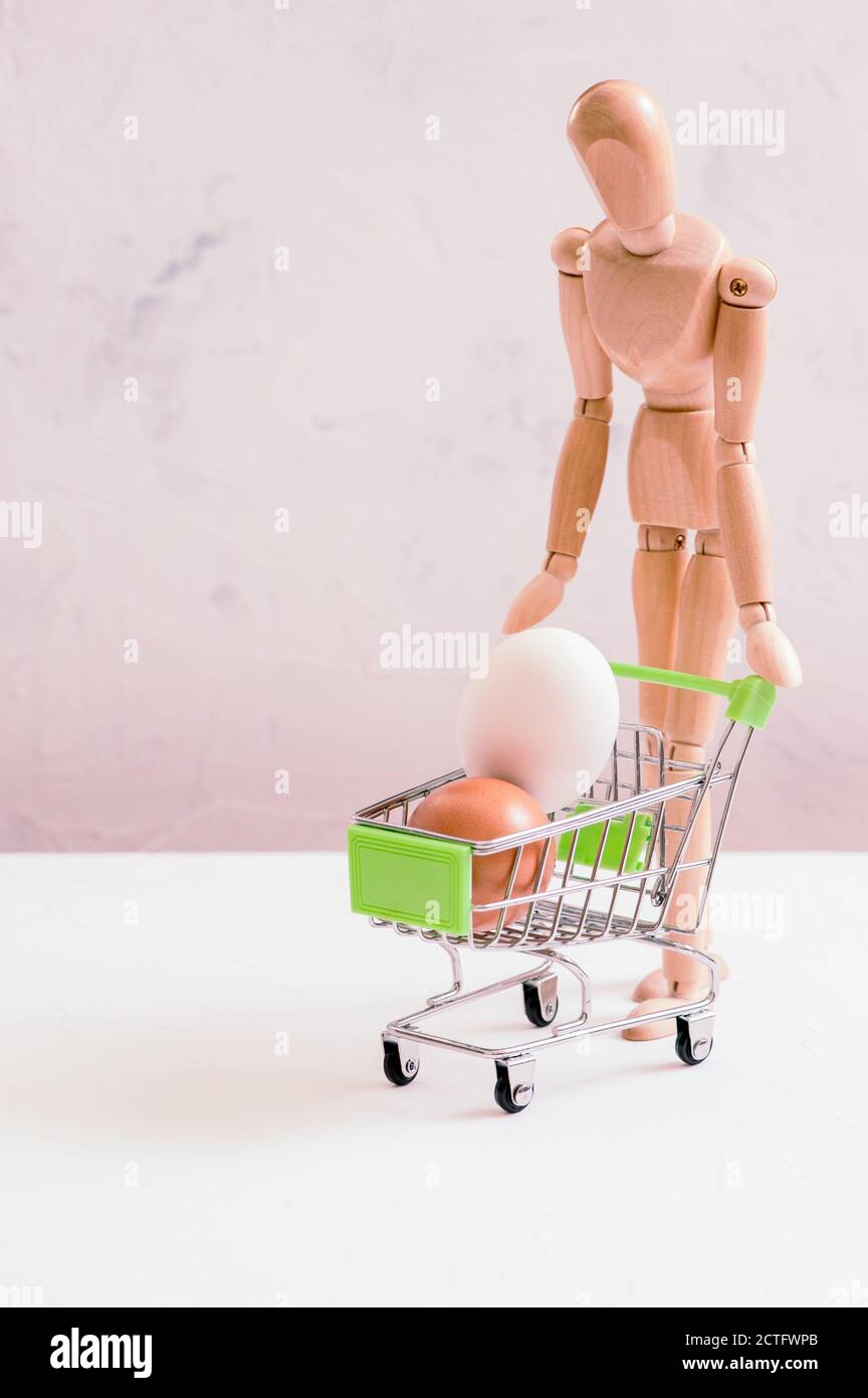 Vertical shot of a gestalt figurine with a shopping cart with eggs in it Stock Photo