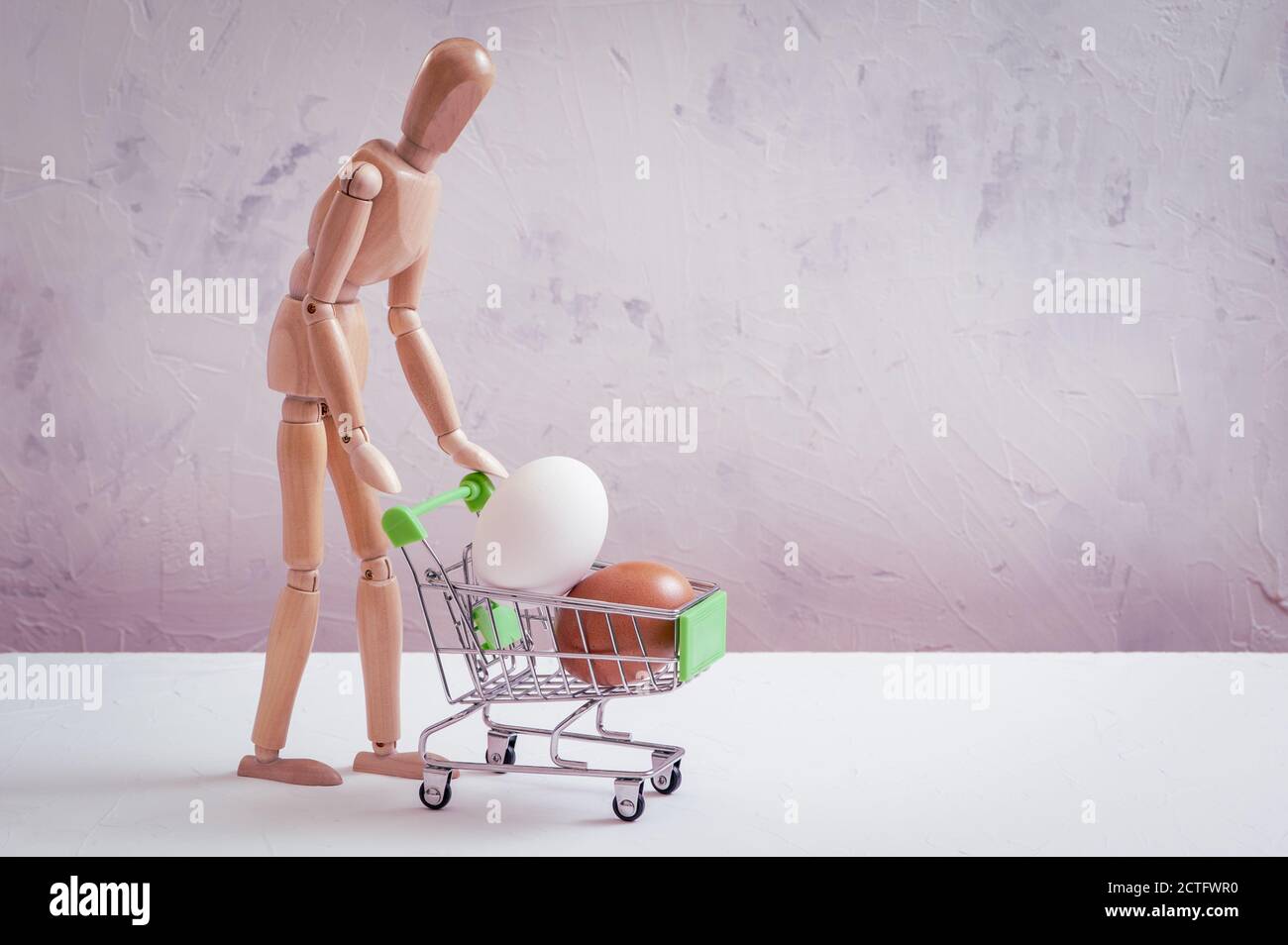 Closeup shot of a gestalt figurine with a shopping cart with eggs in it Stock Photo