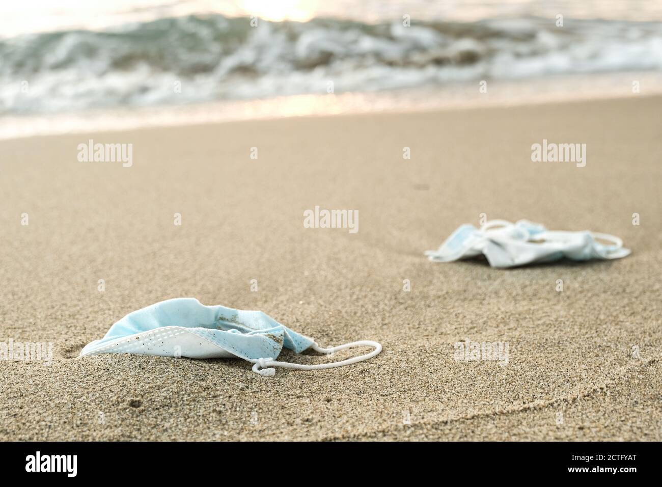 Medical face masks discarded on sea shore,covid19 pandemic disease pollution Stock Photo
