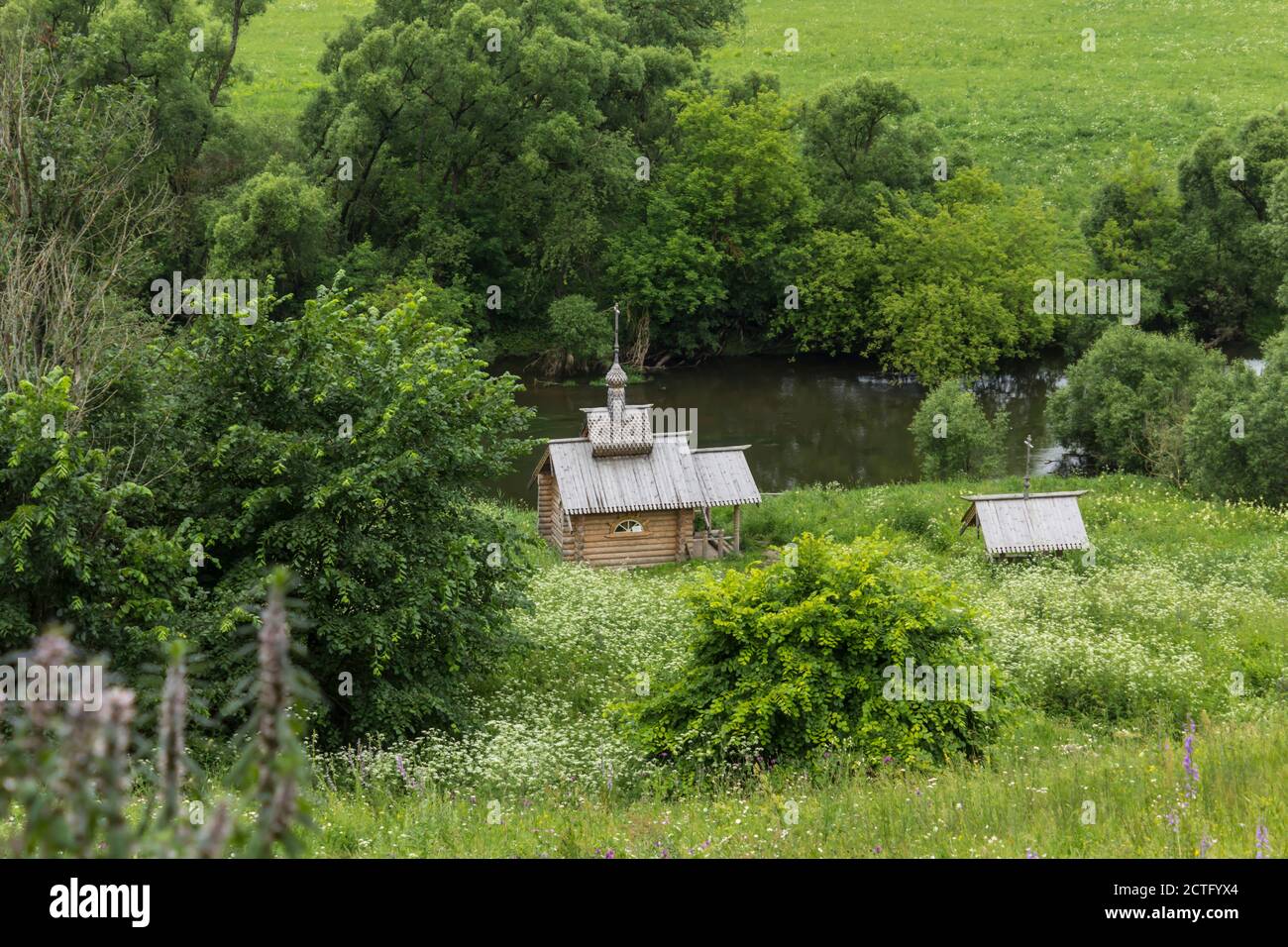 Mid summer . Fresh grass in the meadows. A wooden chapel on the banks of the Protva River in Russia. Great place for tourism. Stock Photo