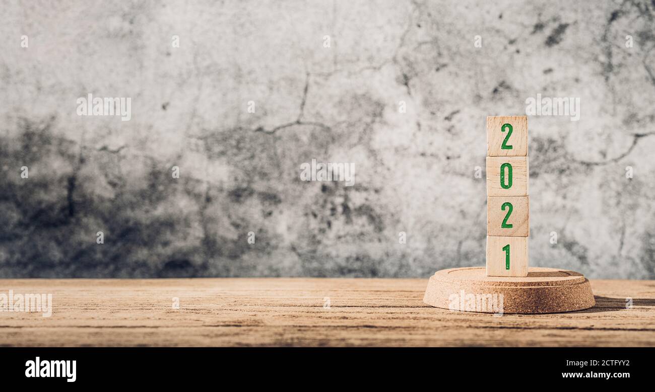 Green 2021 happy new year on wood table and concrete wall background Stock Photo