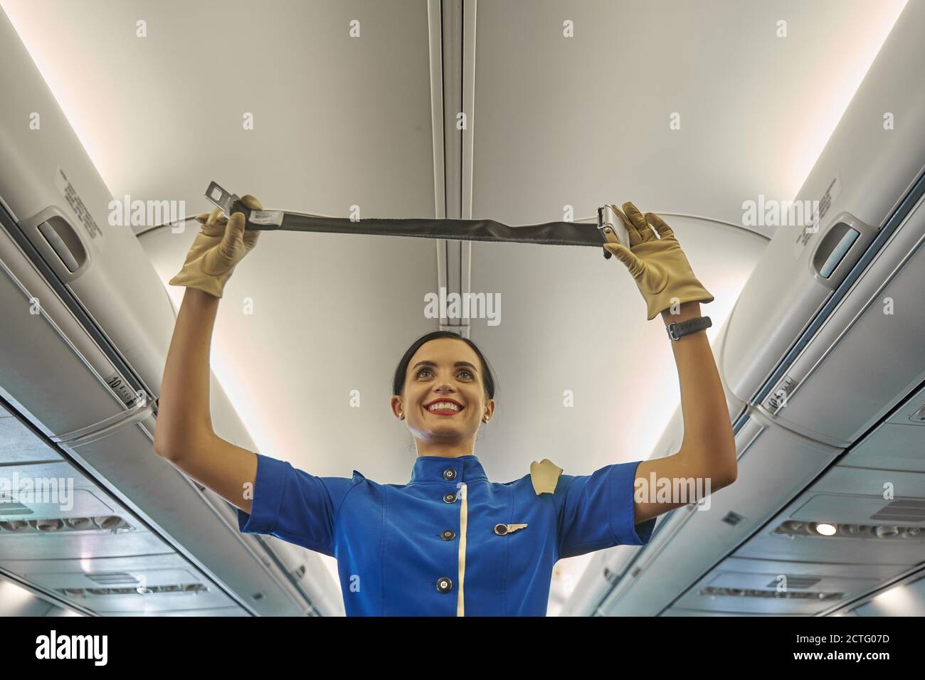 Enthusiastic stewardess demonstrating the seat belt in the plane Stock Photo Alamy
