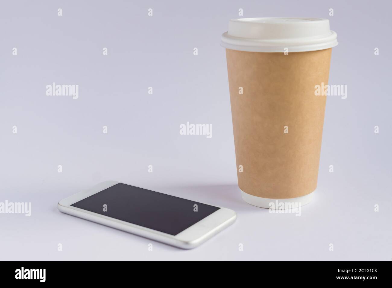 craft paper coffee cup and metallic smartphone on gray background in ...