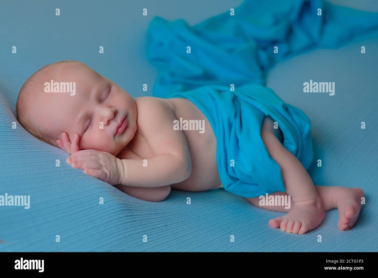Newborn sleeping baby boy on a blue blanket. Stock Photo