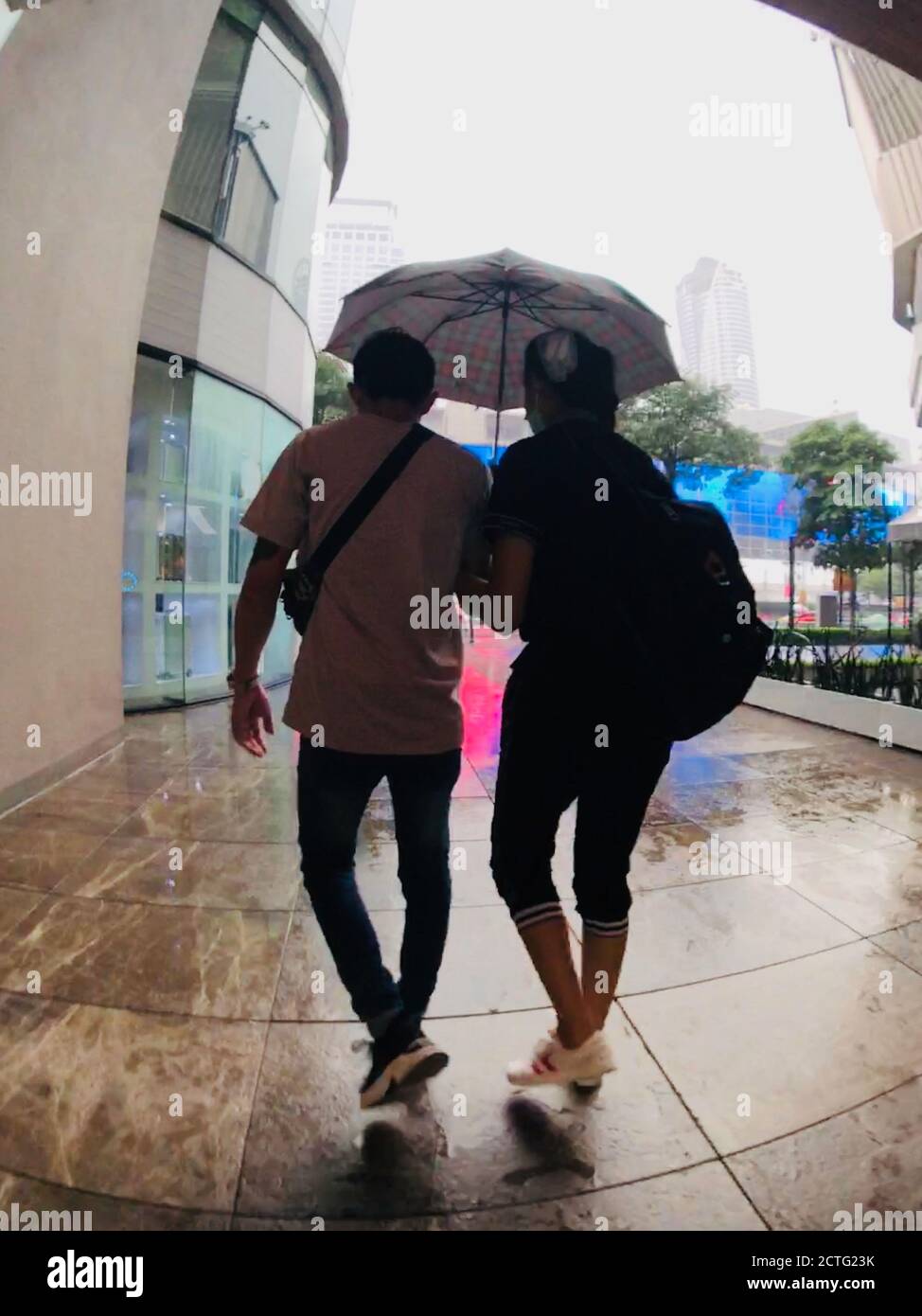 Couple walk in rain with umbrella Stock Photo - Alamy