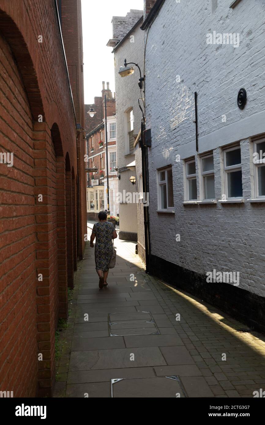 A lady walking along a Narrow lane in Horncastle, Lincolnshire on a sunny day Stock Photo