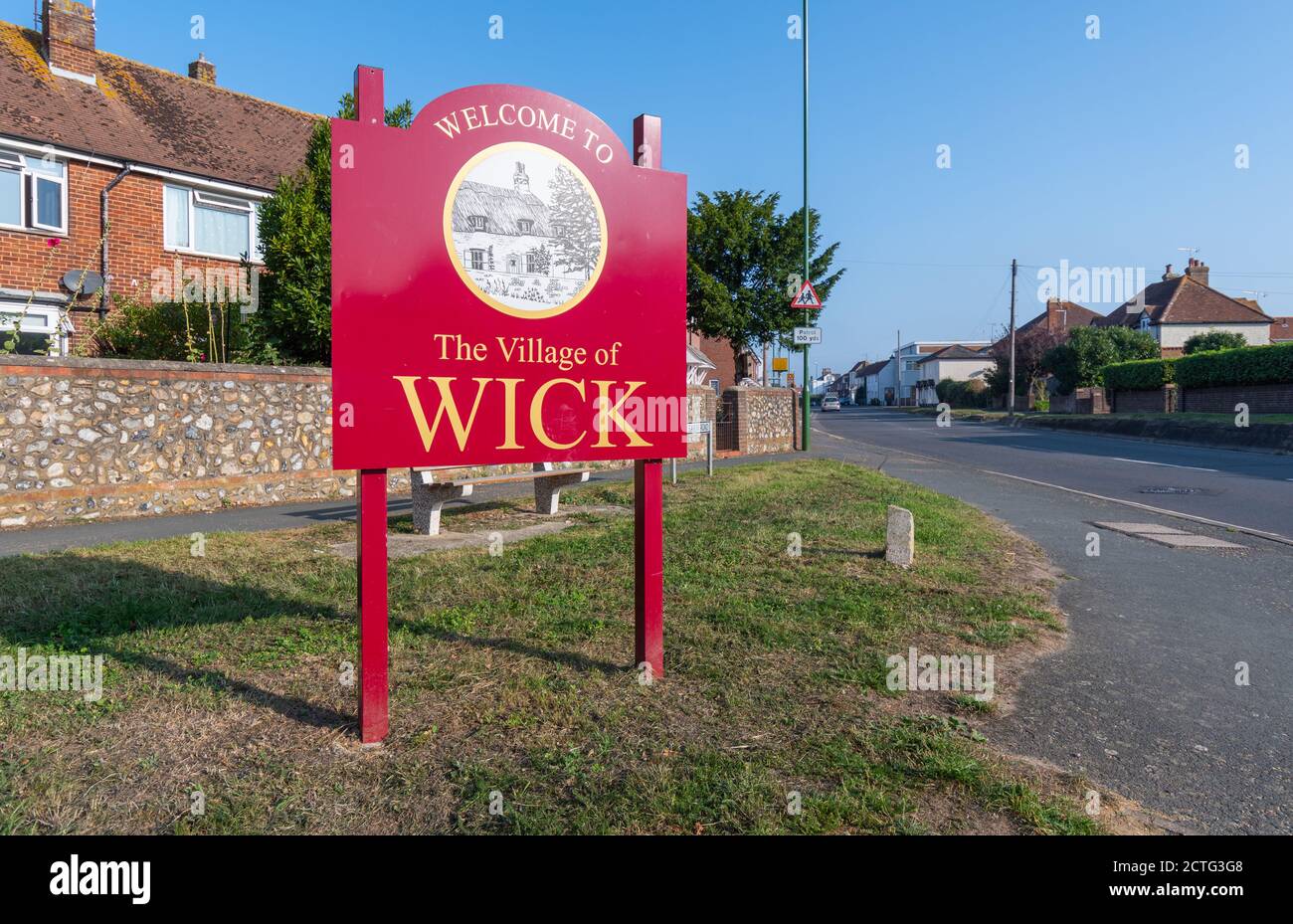 to The Village of Wick sign by a road in Wick, West Sussex