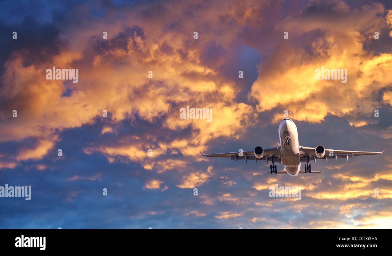 Passenger airplane is flying in colorful sky at sunset Stock Photo - Alamy