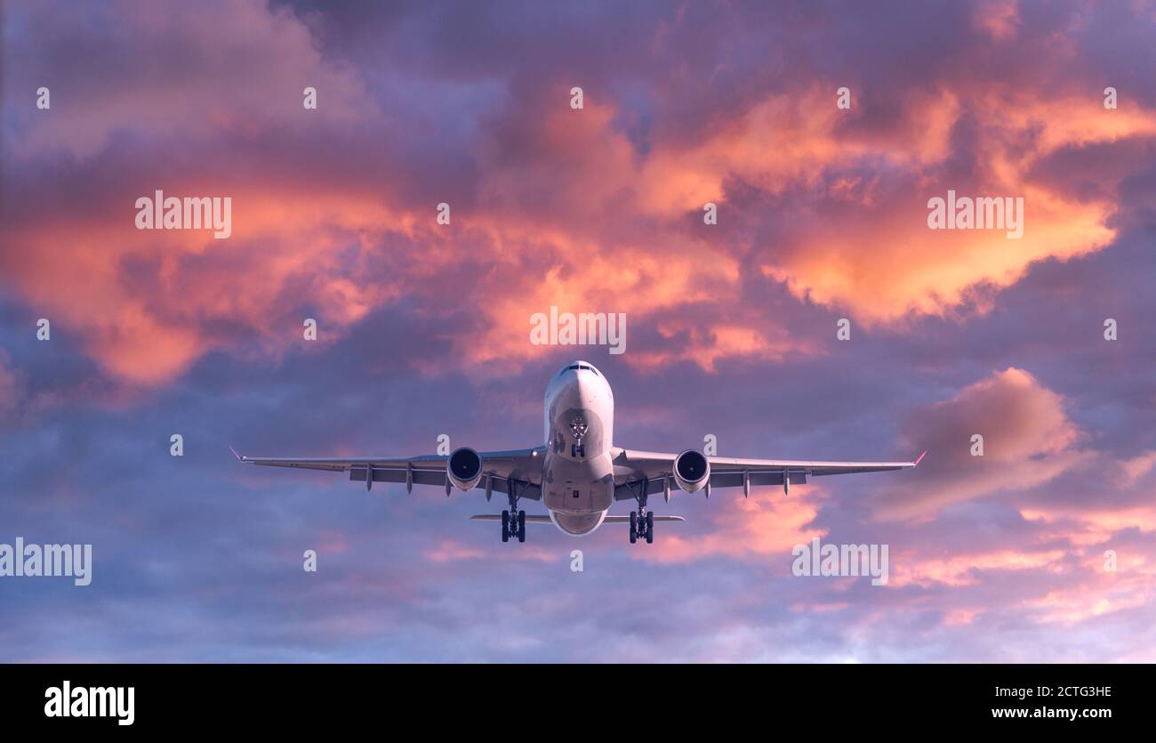 Passenger airplane is flying in colorful sky at sunset Stock Photo