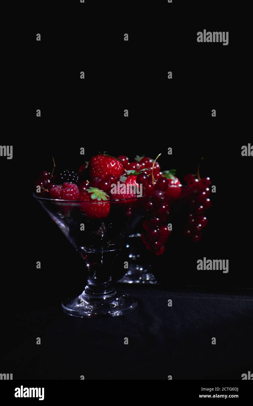 Different red fruits in a glass reflecting in a mirror, strawberries, berries Stock Photo