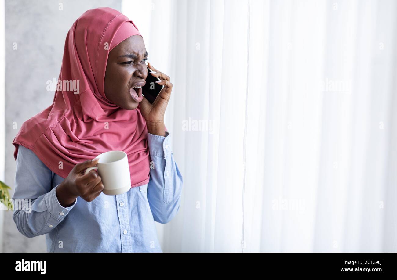 Black Muslim Woman Arguing On Phone And Drinking Coffee, Standing Near ...