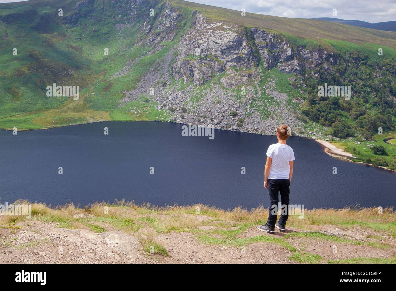 A boy admiring a view to a Lough Tay in Wicklow Mountains National Park in Ireland Stock Photo