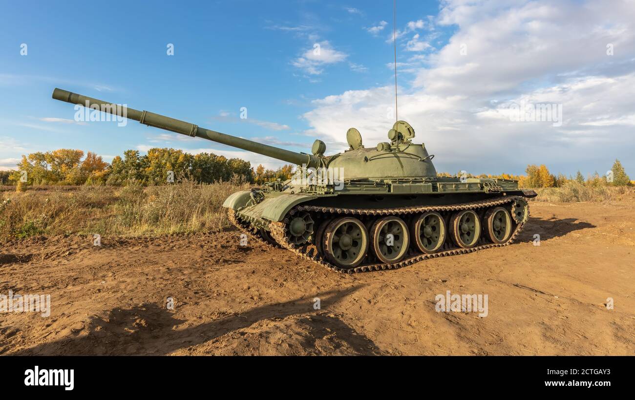 A side shot of old russian tank T-62 in the field. Blue cloudy sky as a background. Stock Photo