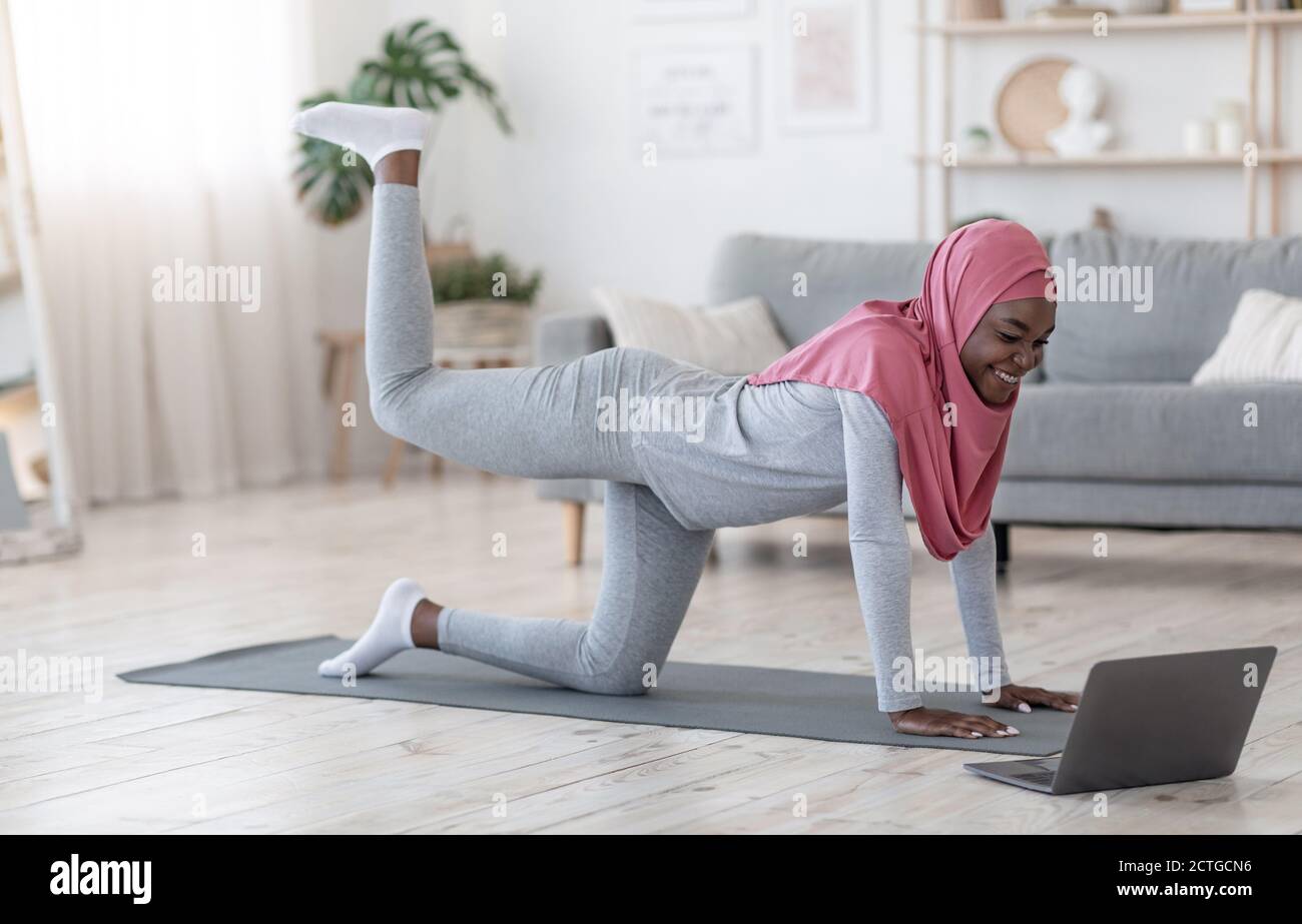Sporty Black Islamic Woman In Hijab Excersising At Home With Laptop Stock Photo