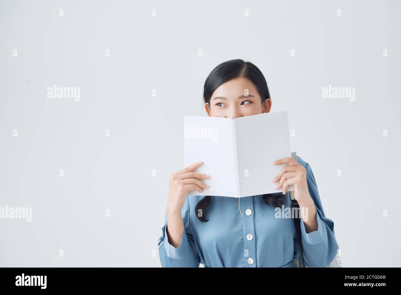Joyful dark-haired girl covers her face with her white notebook Stock Photo