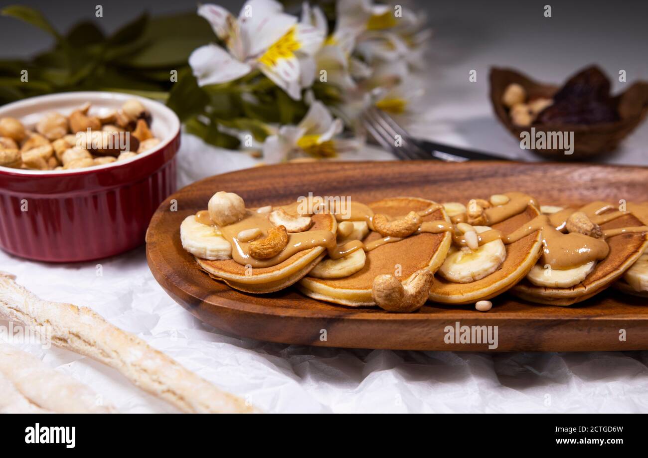 Pancakes with mix of nuts and peanut butter on white background with