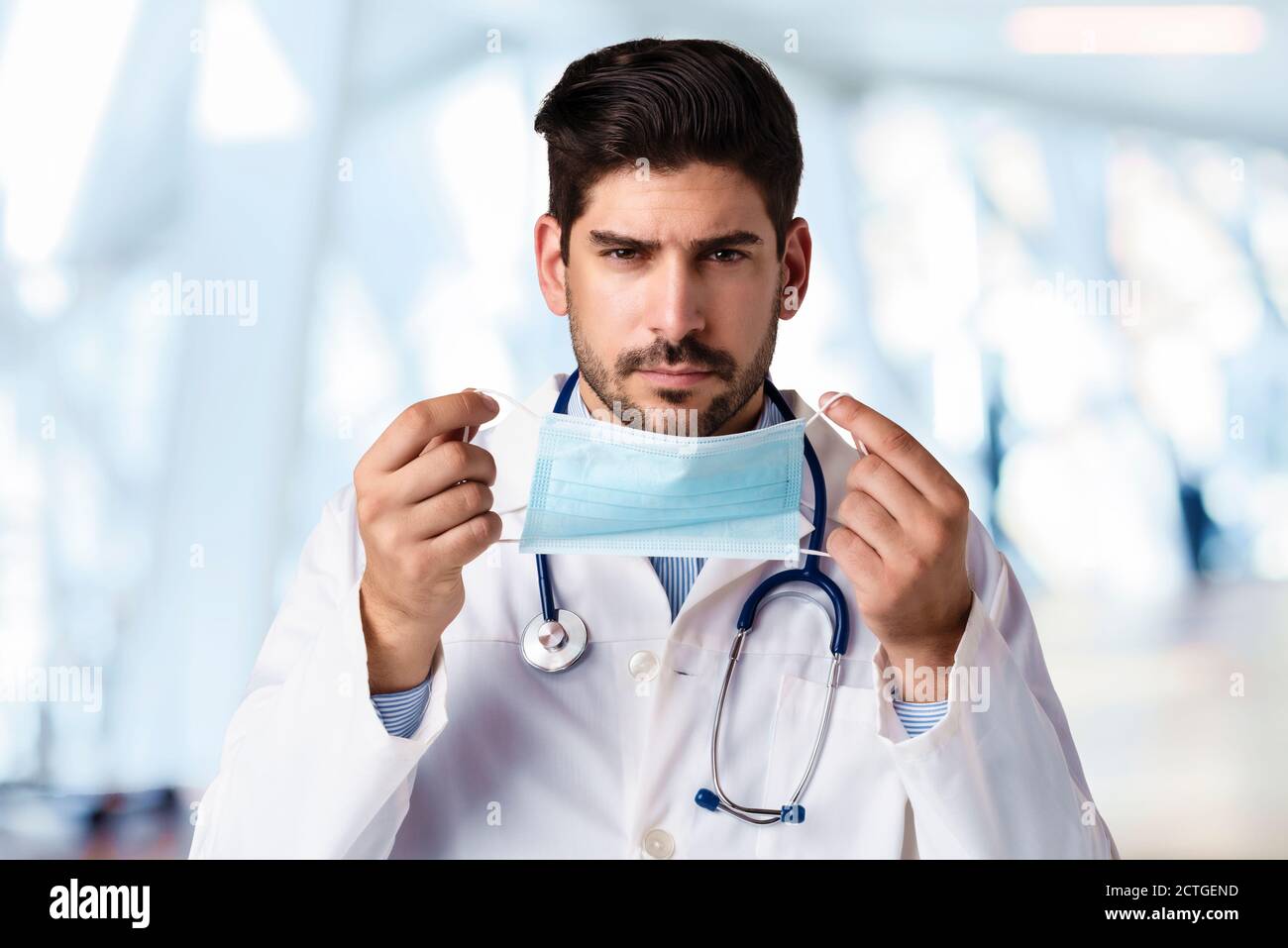 hot of male doctor putting on face mask for prevention while standing in  the hospital's foyer Stock Photo - Alamy