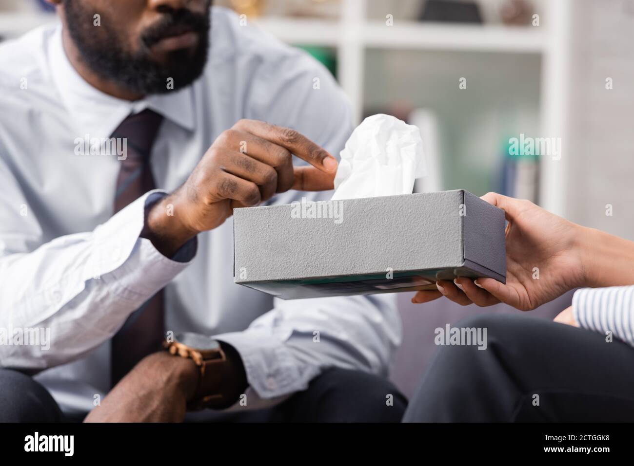 cropped view of african american man taking paper napkin from hands of psychologist Stock Photo