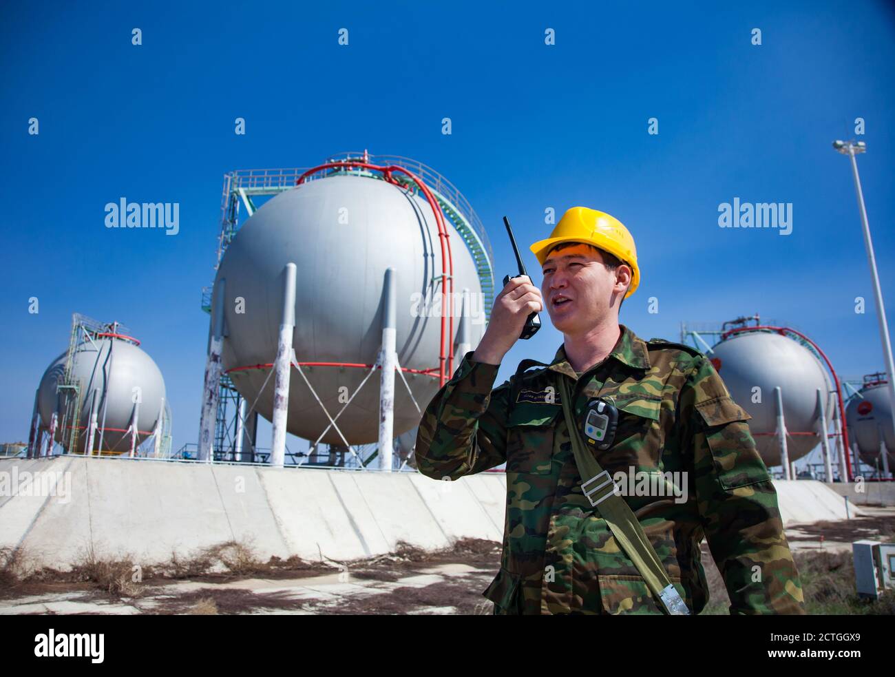Oil refinery and gas processing plant. Asian Security guard with radio