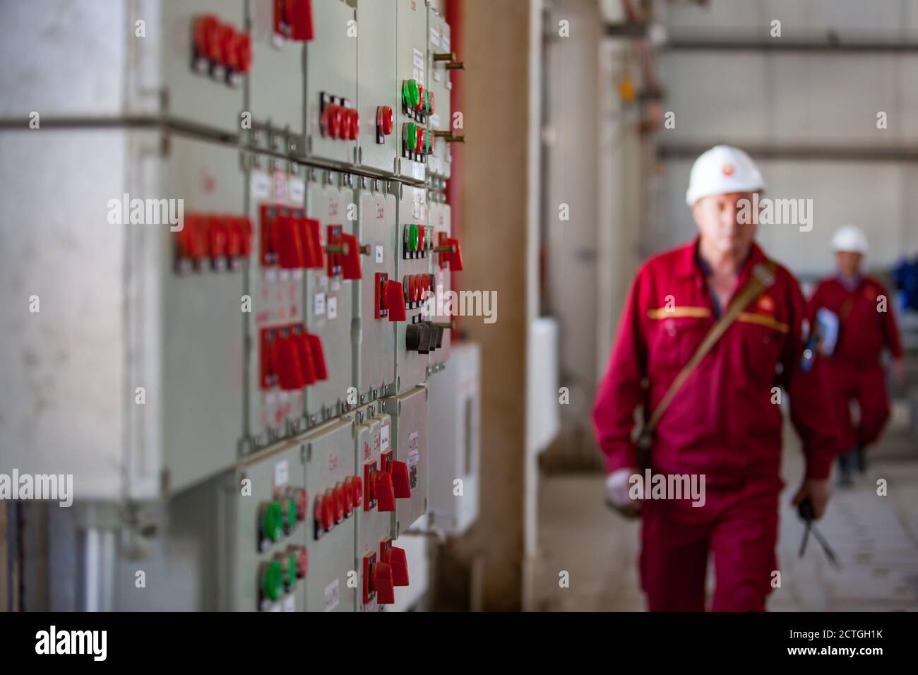 Electric equipment and processing remote control panel (console). Oil refinery and gas processing plant. Blurred refinery workers in white helmet. Stock Photo