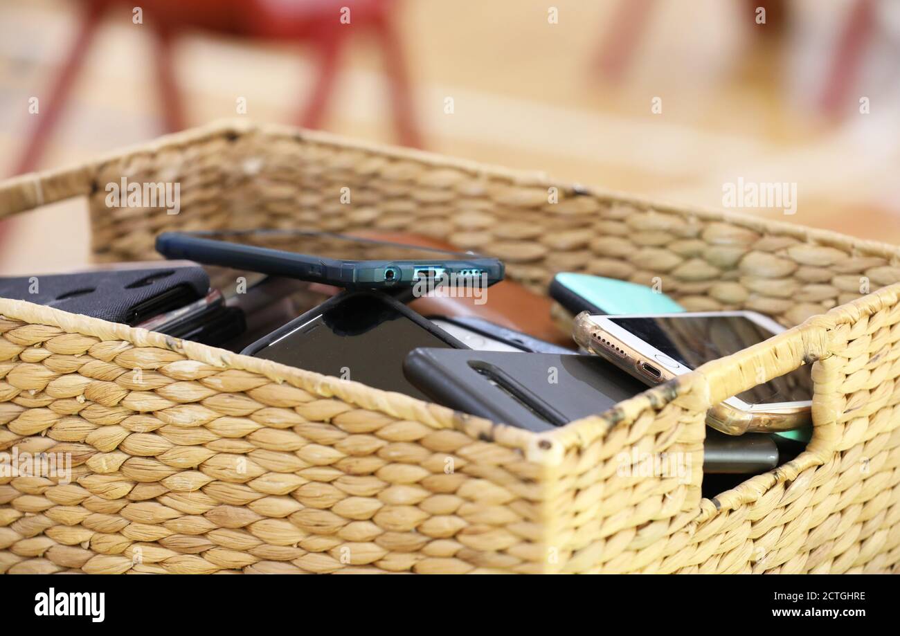 Mobile cell phone free classrooms and schools. A storage Container filled with multiple phones from students or users. Cane basket filled with mobile Stock Photo
