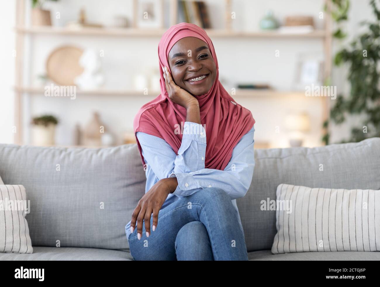 Portrait of happy black muslim woman in hijab on couch at home Stock ...