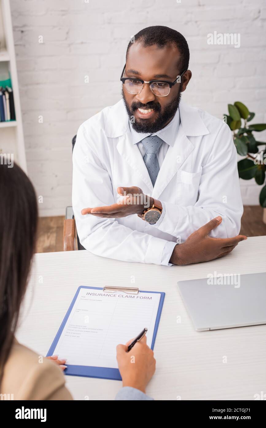 selective focus of african american doctor in eyeglasses pointing with